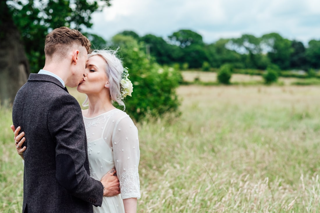 bride and groom kissing in a field
