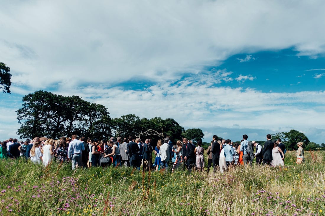 guests waiting in field at outdoor wedding ceremony in a meadow