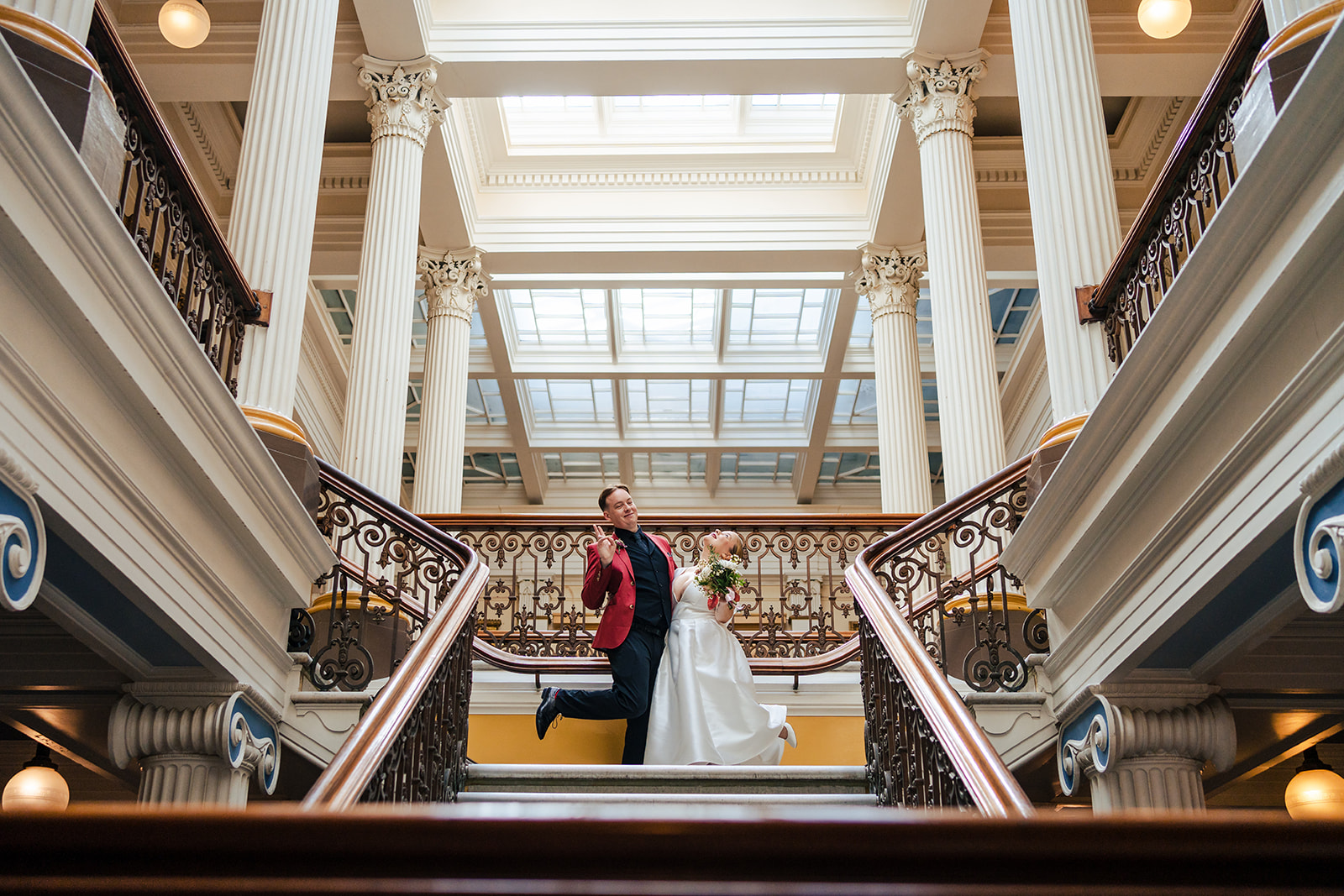 A bride and groom standing on the stairs of a building.